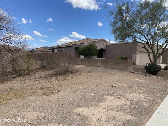 exterior space with stucco siding, fence, an attached garage, and a tile roof