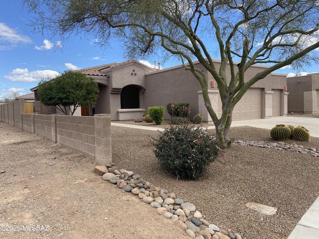 view of front of house featuring an attached garage, driveway, a fenced front yard, and stucco siding