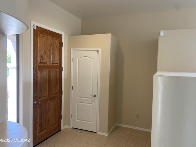 corridor with light tile patterned flooring and baseboards