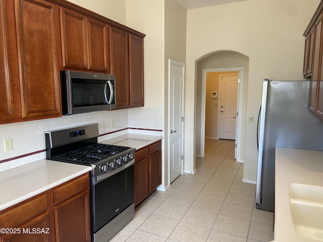 kitchen with light countertops, light tile patterned floors, backsplash, and stainless steel appliances