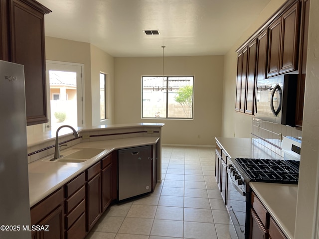 kitchen featuring light tile patterned floors, a healthy amount of sunlight, stainless steel appliances, and a sink