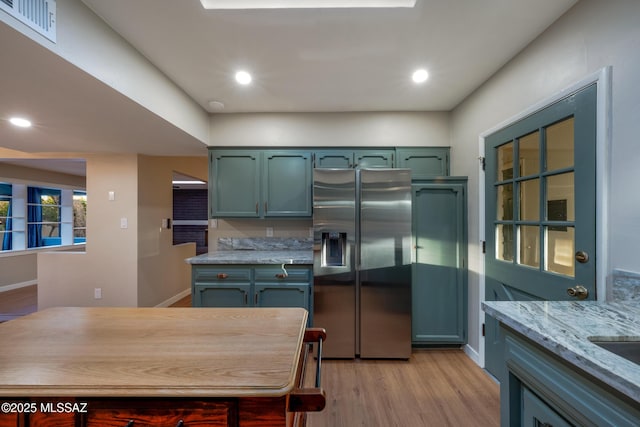 kitchen featuring visible vents, light stone countertops, light wood-type flooring, recessed lighting, and stainless steel refrigerator with ice dispenser