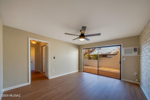 unfurnished bedroom featuring access to exterior, baseboards, wood finished floors, and a wall mounted AC