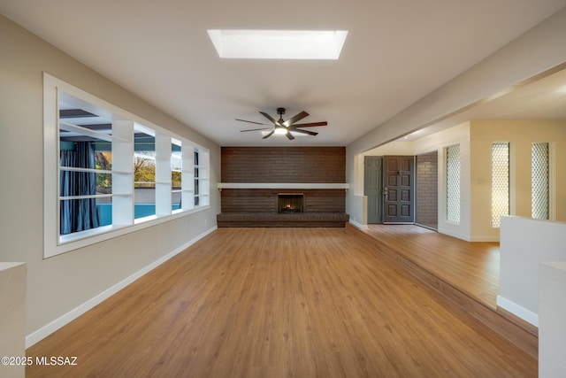 unfurnished living room featuring a brick fireplace, a ceiling fan, baseboards, and light wood finished floors