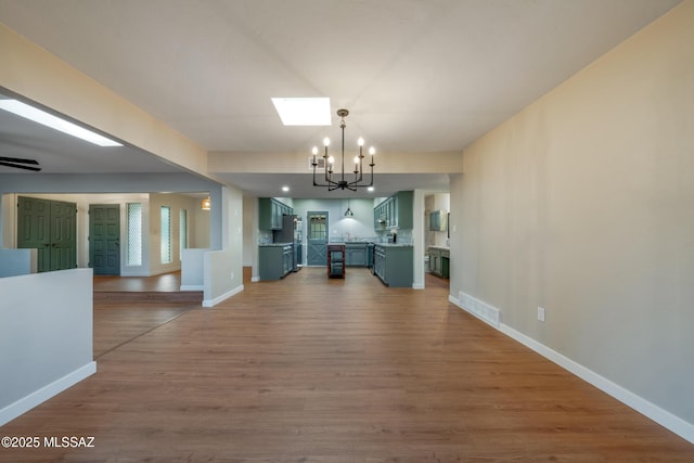 unfurnished dining area with visible vents, dark wood-type flooring, a skylight, baseboards, and a chandelier