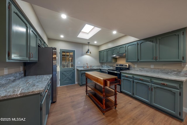 kitchen featuring a skylight, wood finished floors, under cabinet range hood, and stainless steel appliances