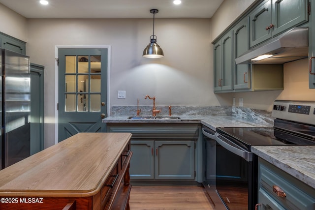 kitchen featuring under cabinet range hood, light stone counters, a sink, light wood-style floors, and appliances with stainless steel finishes