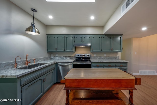 kitchen with under cabinet range hood, visible vents, stainless steel appliances, and a sink