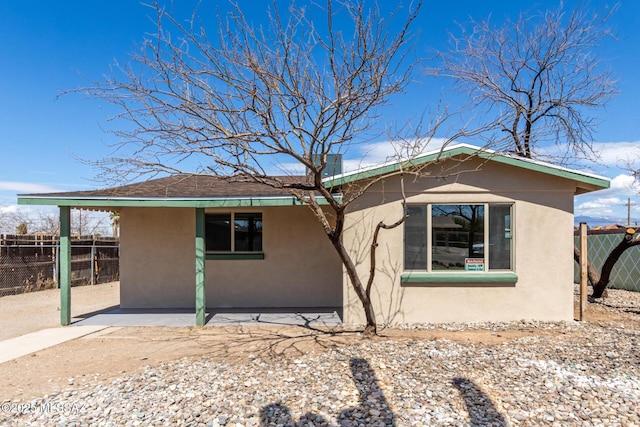 rear view of property featuring stucco siding, a patio, and fence