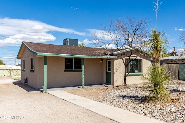 ranch-style house featuring stucco siding and fence