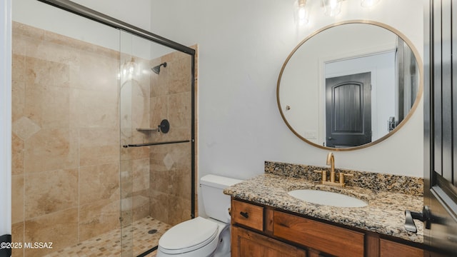 full bath with vanity, a shower stall, and toilet