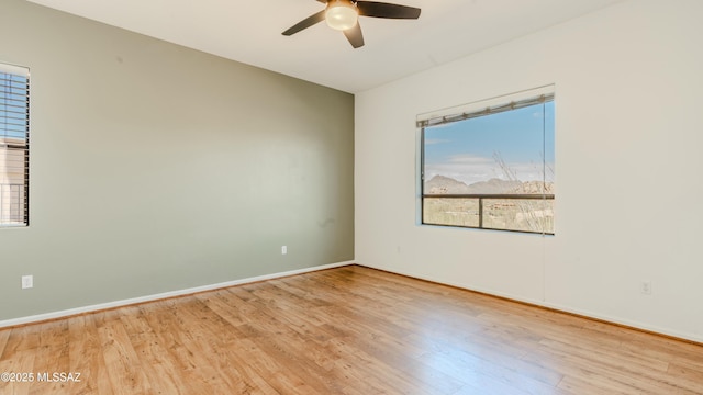 empty room featuring wood finished floors, a ceiling fan, and baseboards