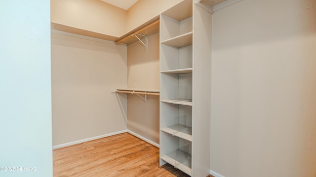 walk in closet with wood finished floors