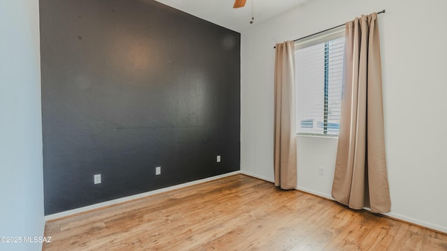 empty room with baseboards, wood finished floors, and a ceiling fan