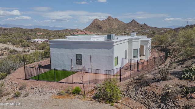 view of property exterior with cooling unit, a mountain view, a chimney, and fence