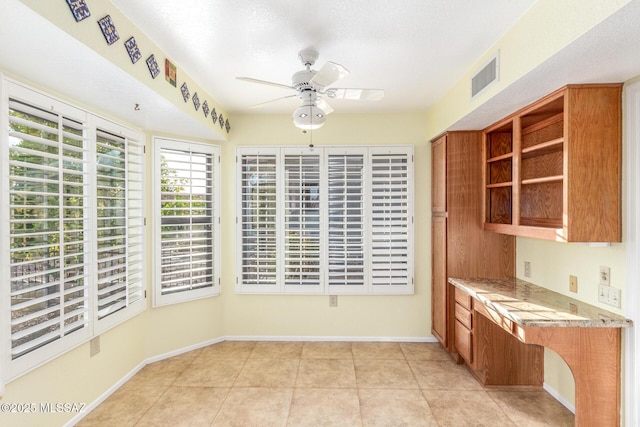 kitchen featuring visible vents, brown cabinetry, open shelves, ceiling fan, and light tile patterned floors