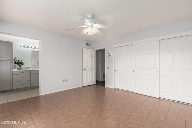 unfurnished bedroom with visible vents, a closet, baseboards, ceiling fan, and ensuite bath