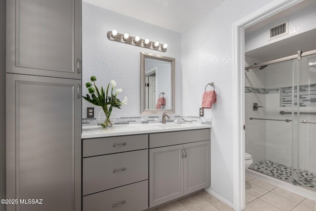 bathroom with vanity, toilet, visible vents, and a stall shower