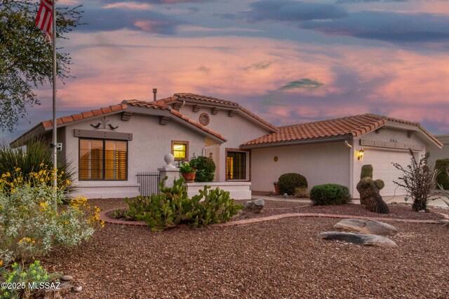mediterranean / spanish-style house with stucco siding, a tile roof, and a garage