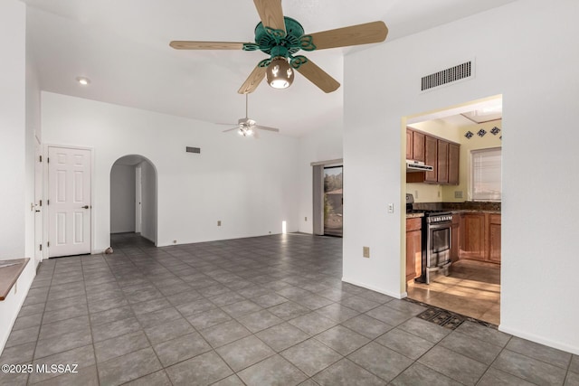 unfurnished living room with arched walkways, ceiling fan, visible vents, and a towering ceiling