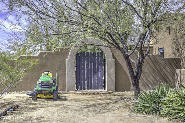 view of side of home with a gate, fence, and stucco siding