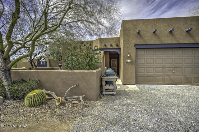 pueblo-style home with stucco siding and an attached garage