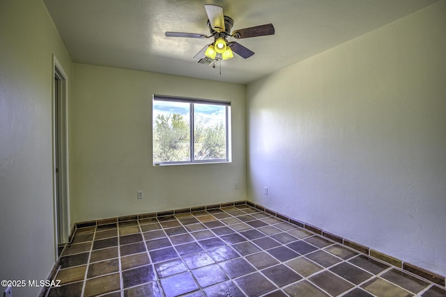 unfurnished room with dark tile patterned floors, a ceiling fan, and visible vents