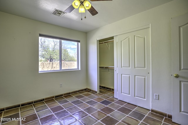 unfurnished bedroom with a closet, visible vents, ceiling fan, and dark tile patterned flooring