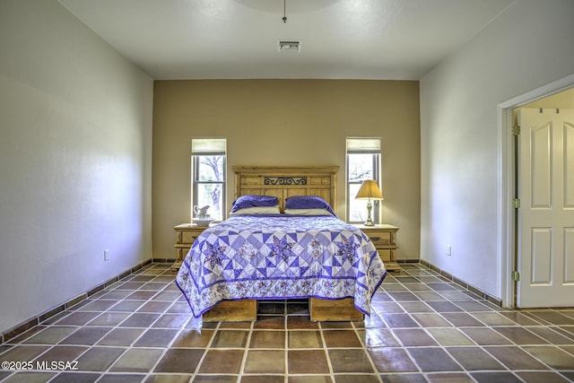 unfurnished bedroom with tile patterned floors, visible vents, multiple windows, and baseboards