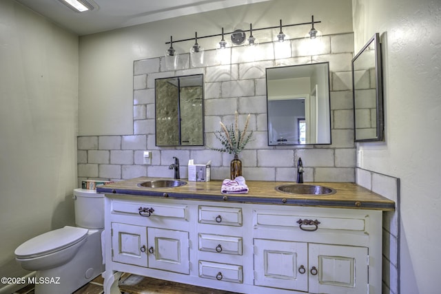 full bathroom with double vanity, toilet, tasteful backsplash, and a sink