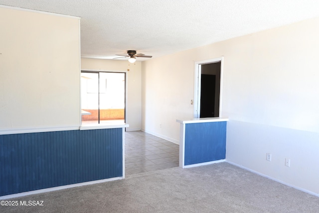 tiled empty room with carpet flooring, a ceiling fan, and a textured ceiling