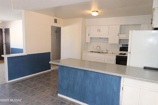 kitchen featuring visible vents, freestanding refrigerator, range with gas stovetop, under cabinet range hood, and white cabinetry