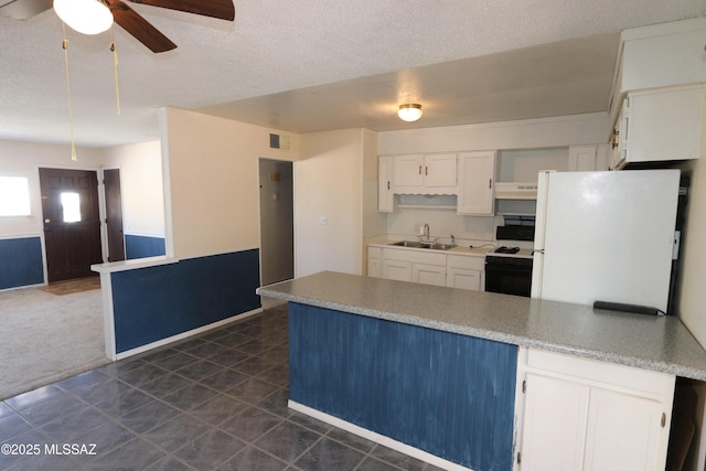 kitchen featuring a sink, white cabinets, freestanding refrigerator, a peninsula, and range with gas stovetop