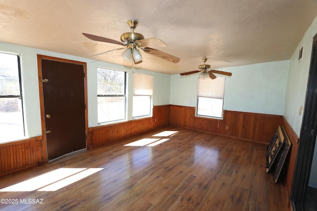 spare room featuring wooden walls, ceiling fan, wainscoting, and wood finished floors