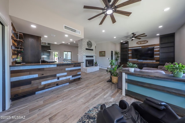 living area featuring visible vents, recessed lighting, light wood-style flooring, a fireplace, and a ceiling fan