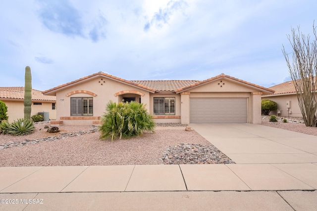 view of front of home featuring stucco siding, a tile roof, central AC, concrete driveway, and a garage