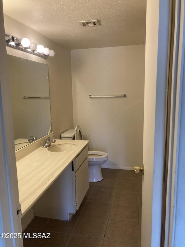 bathroom featuring visible vents, toilet, vanity, tile patterned floors, and a textured ceiling