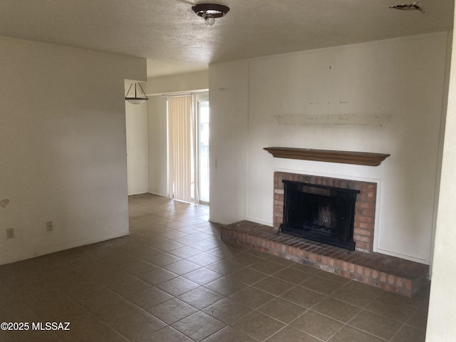 unfurnished living room with dark tile patterned flooring, a brick fireplace, and a textured ceiling