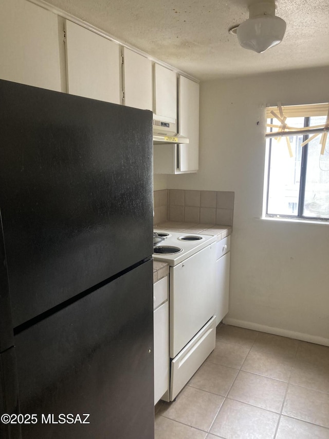 kitchen with range hood, light tile patterned floors, freestanding refrigerator, electric stove, and a textured ceiling