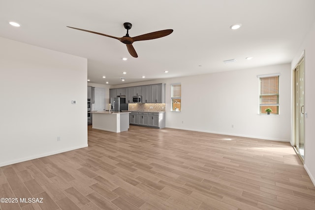 unfurnished living room with recessed lighting, light wood-type flooring, baseboards, and ceiling fan