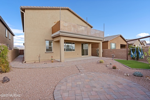 rear view of house with a patio, a fenced backyard, and stucco siding