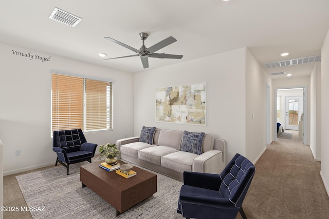 living area featuring visible vents, carpet, and a ceiling fan