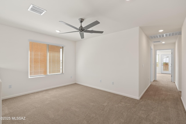 carpeted empty room with a ceiling fan, visible vents, and baseboards