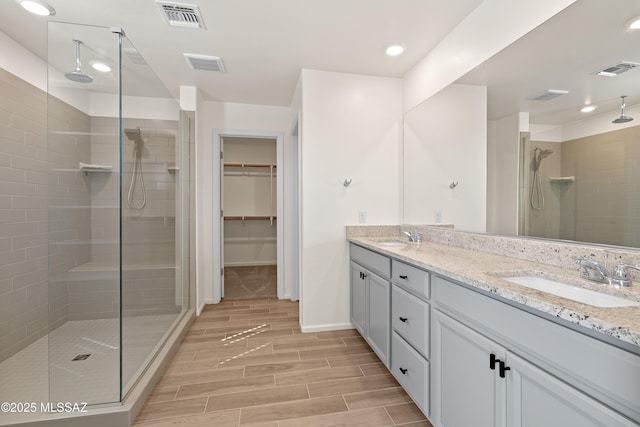 bathroom featuring a sink, visible vents, wood finish floors, and a stall shower