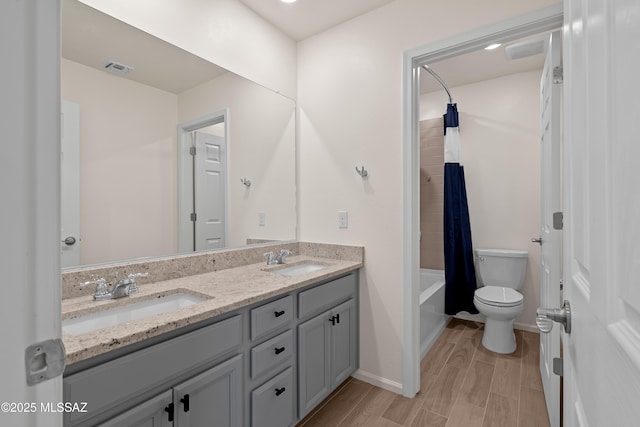 bathroom with a sink, toilet, double vanity, and wood tiled floor