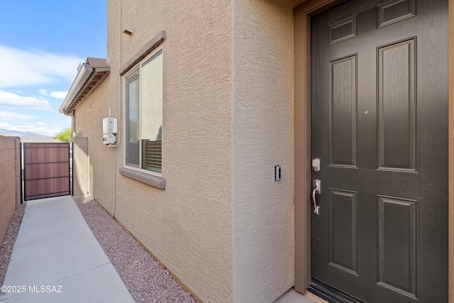 entrance to property with stucco siding and fence