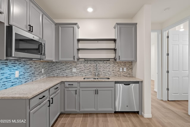 kitchen with a sink, open shelves, gray cabinetry, and stainless steel appliances