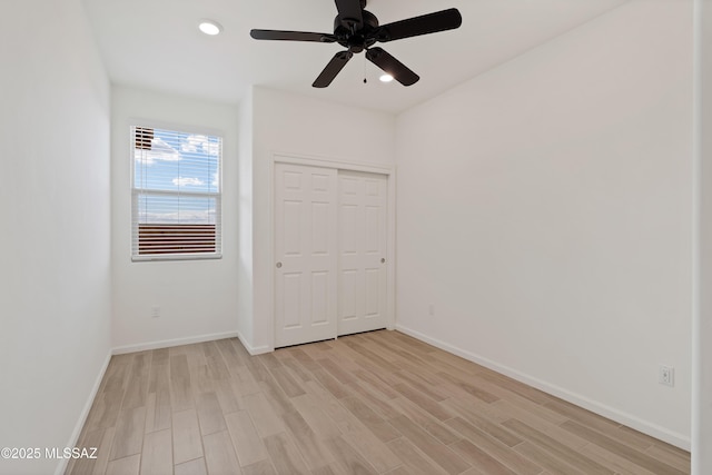 unfurnished bedroom with a closet, recessed lighting, light wood-style flooring, and baseboards