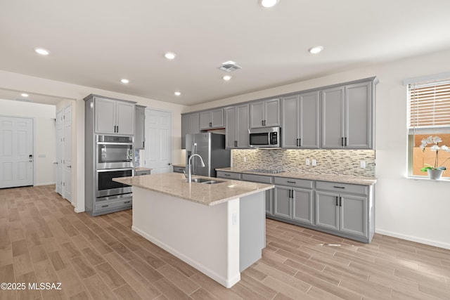 kitchen featuring visible vents, gray cabinets, a sink, backsplash, and stainless steel appliances