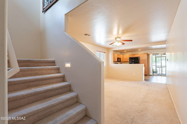 stairway featuring carpet flooring, a ceiling fan, baseboards, and visible vents